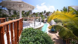 Ein Poolbereich mit Holzterrasse, Liegestühlen und Sonnenschirmen.