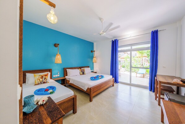 A hotel room with two beds, a dining table, a ceiling fan, and a view of the outdoors. - Olzadia Boutique Hotel (Michamvi)