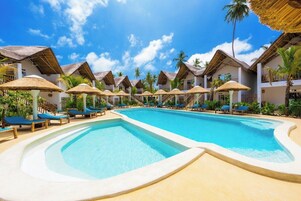 Una piscina al aire libre, sombrillas, sillones reclinables de piscina