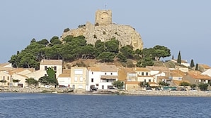 Un pueblo costero con edificios sobre una colina rocosa y una masa de agua al frente.