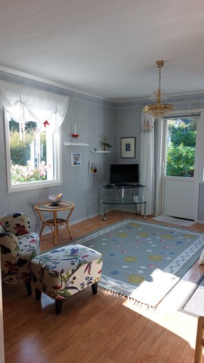 A living room with a television, a dining table, and a sofa.