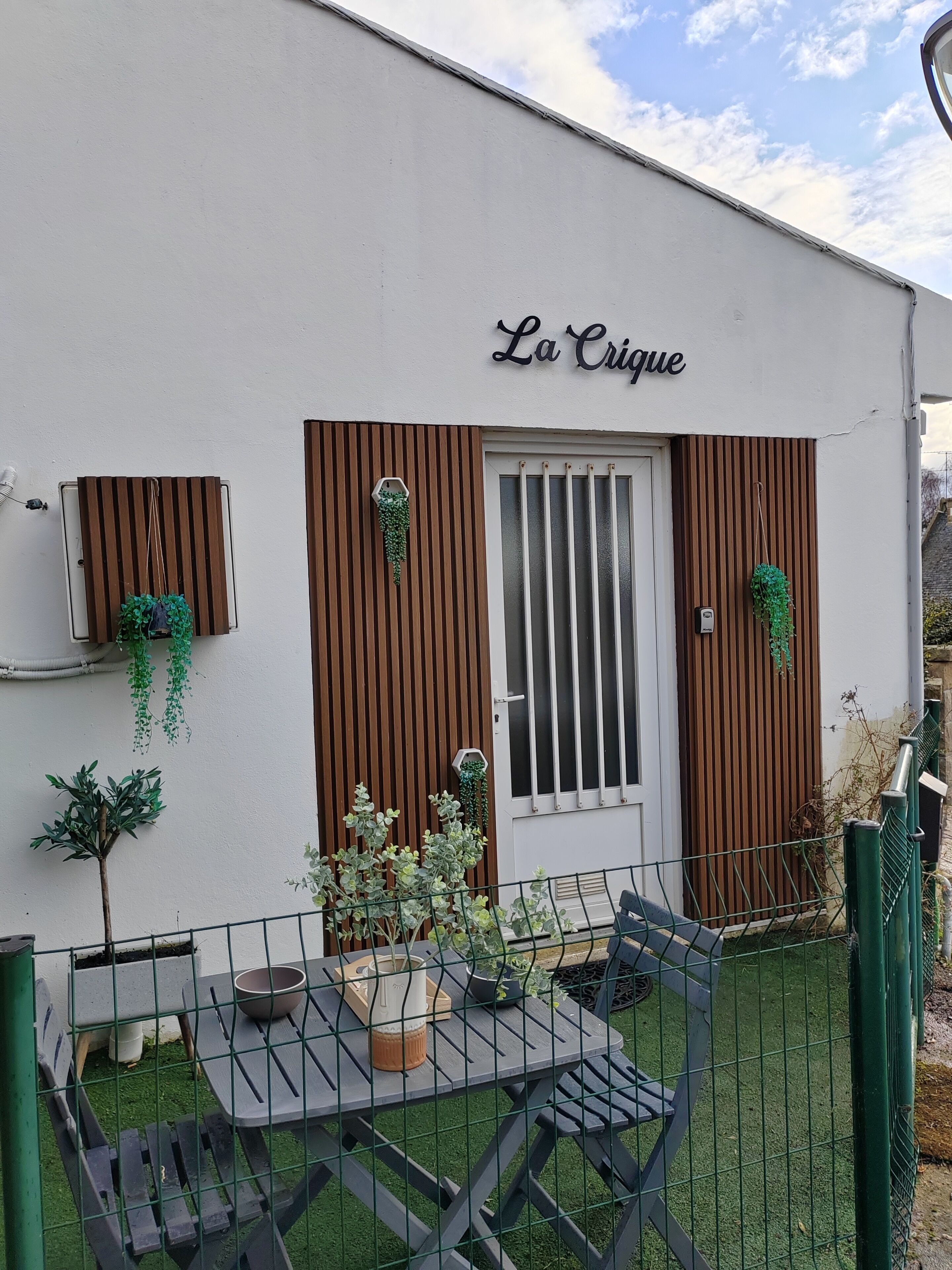 A building with the sign "La Crique" and a fenced outdoor seating area with tables and chairs.