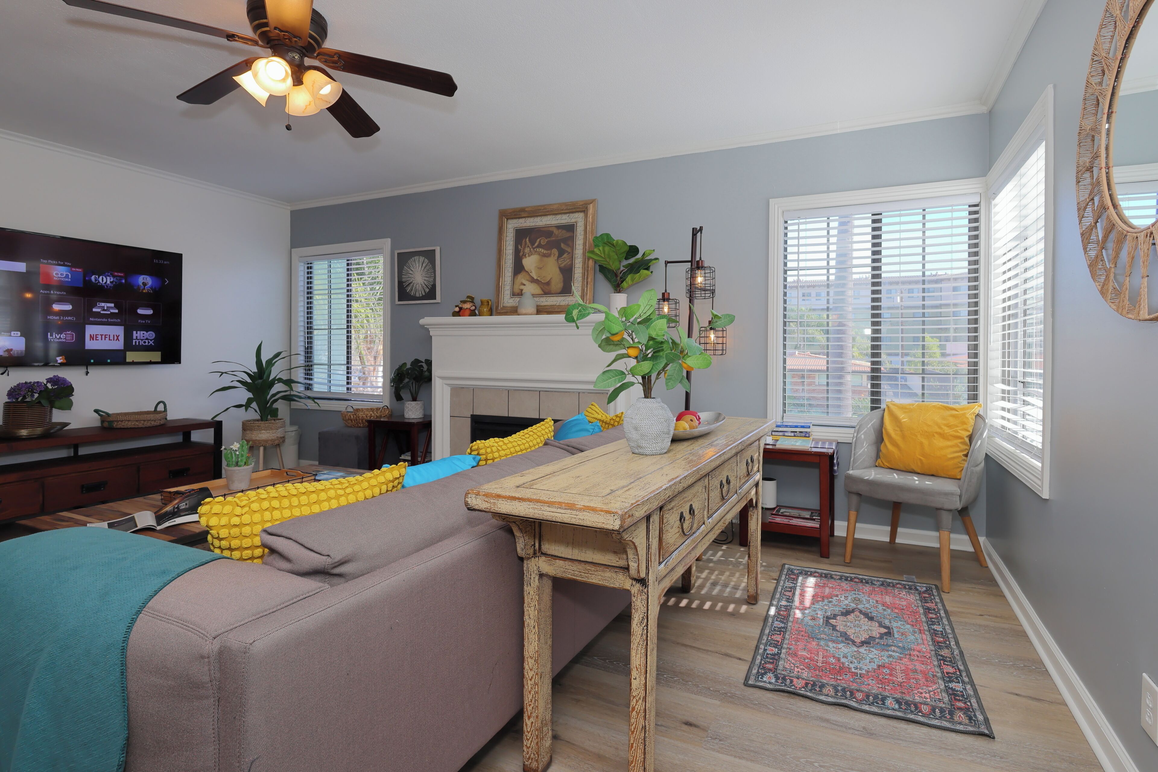 A living room with a sofa, a coffee table, a fireplace, and a TV mounted on the wall.