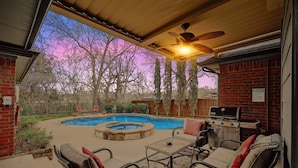 A backyard with a swimming pool, a barbecue grill, and outdoor seating.