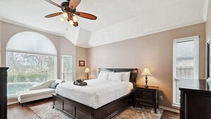 A bedroom with a large bed, a ceiling fan, and two bedside lamps.