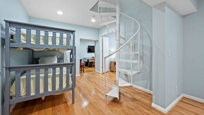 Ein Zimmer mit Etagenbetten, einer Wendeltreppe und einem Holzboden.