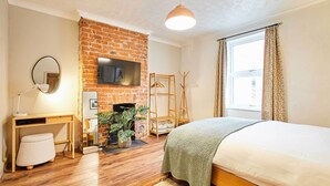 Ein Schlafzimmer mit Kamin aus Ziegelsteinen, einem Bett, einem Schreibtisch und einem Fernseher.