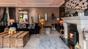 A cozy living room with a fireplace, a large mirror, and a plush sofa.