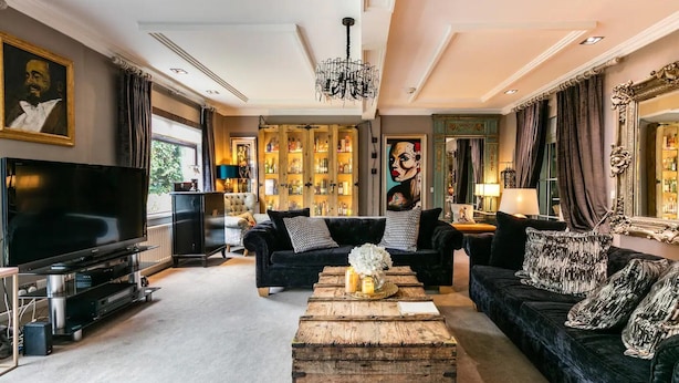 A spacious living room with a large flat-screen TV, a wooden coffee table, and a chandelier.