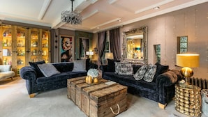 A luxurious living room with two dark sofas, a wooden coffee table, and a large mirror.