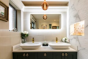 A bathroom with two sinks, a large mirror, and a decorative light fixture. - The Cool Belfast Home (Newtownabbey)