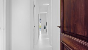 A hallway with white walls and a wooden door.