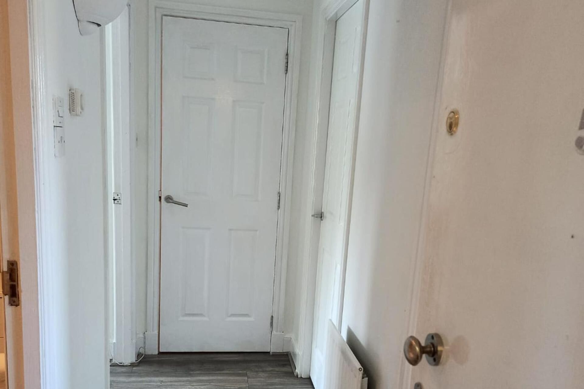 A narrow hallway with a white door at the end.