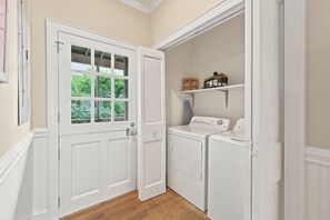 A laundry room with a white door, a window, and two washing machines. - Cubbage - Oceanfront, 5-bedrooms (Pawleys Island)