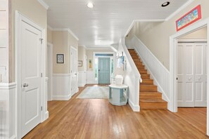 A hallway with wooden flooring, white doors, a staircase, and a blue accent wall. - Cubbage - Oceanfront, 5-bedrooms (Pawleys Island)