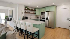 Una cocina moderna con una isla central, electrodomésticos de acero inoxidable y muebles color verde claro.