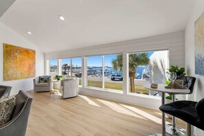 Una sala de estar moderna con ventanas amplias, un sofá, una mesa de centro y una silla.