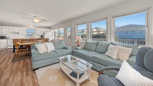 A spacious living room with a sectional sofa, a glass coffee table, and a dining area with a wooden table and chairs. - Direct Beach Access at my newly updated cottage in Nags Head, NC (Nags Head)