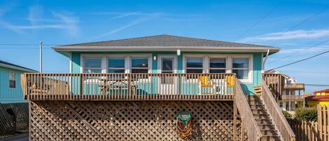 A two-story house with a balcony, a wooden fence, and a staircase leading to the upper level.