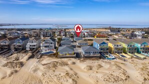 A coastal residential area with colorful houses, sandy dunes, and a body of water in the background. - Direct Beach Access at my newly updated cottage in Nags Head, NC (Nags Head)