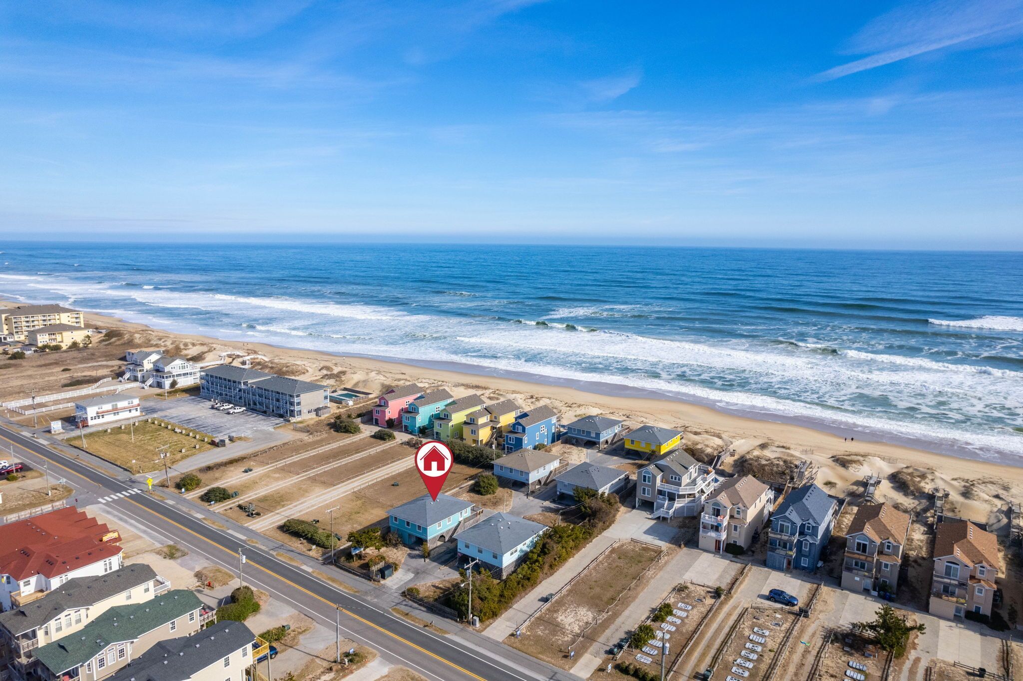 Vue aérienne d’une zone résidentielle côtière, avec des maisons, une plage et une route.