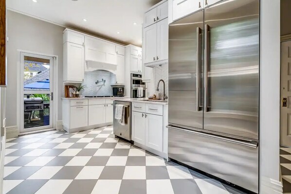 Une cuisine moderne avec des meubles blancs, des appareils en acier inoxydable et un carrelage à motifs.