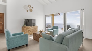 Un salon moderne comprenant un canapé, des fauteuils, une table basse et un téléviseur.