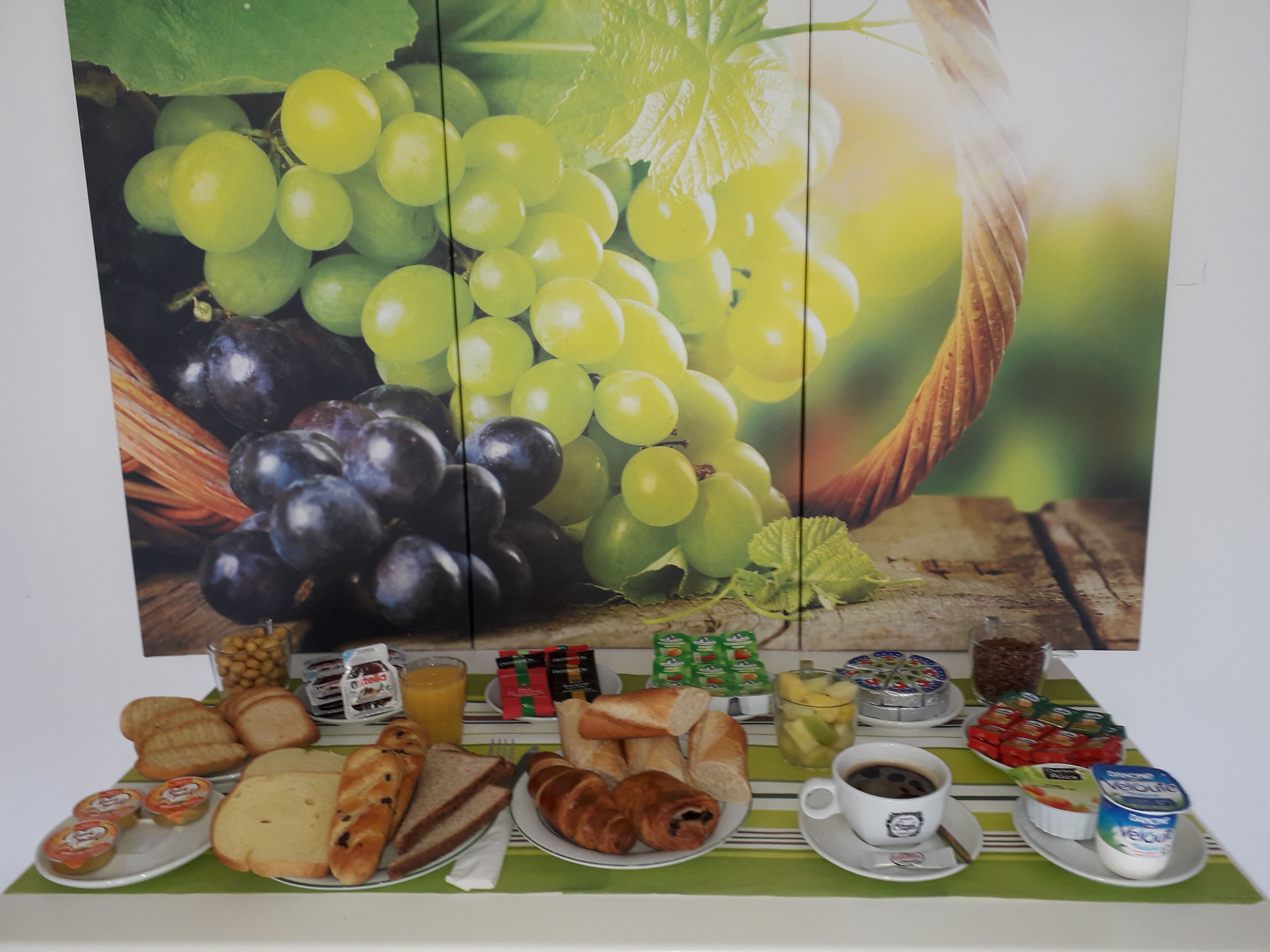 A breakfast buffet with various food items and a large fruit painting.