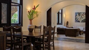 A dining area with a wooden table and chairs, a vase with flowers, and a sofa in the background. - Casa Las Brisas – Caribbean Vacation Rental (Cabarete)
