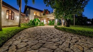A stone-paved pathway leading to a building with a tiled roof and arched windows. - Casa Las Brisas – Caribbean Vacation Rental (Cabarete)