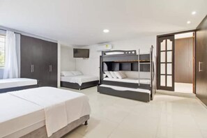 Cozy accommodations feature a large bed, a smaller bed with a dark headboard, and a bunk bed, along with a mounted television and a large window.