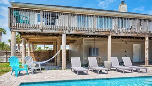 Un área junto a la piscina con sillones de descanso, una hamaca y una terraza de madera.
