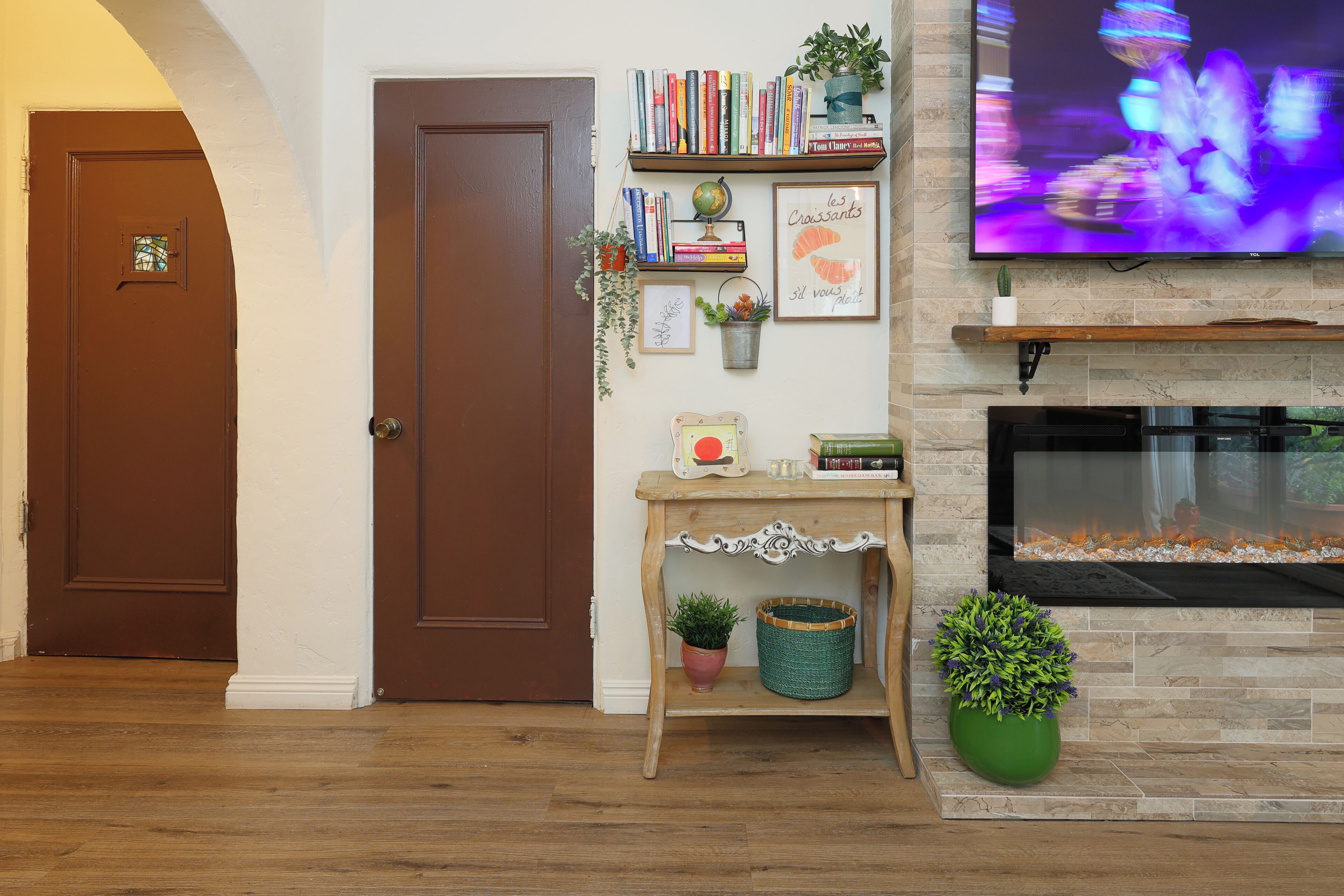 Ein Wohnzimmer mit Kamin, einem darüber montierten Fernseher und einer Bücherwand mit Büchern und Dekoration.
