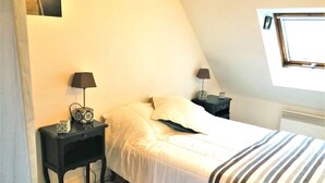 A bedroom with a bed, two bedside tables with lamps, a patterned rug, and a window with blinds.