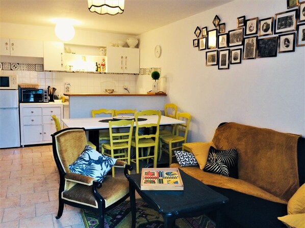 A compact living space with a dining area, kitchenette, and a sofa with cushions.