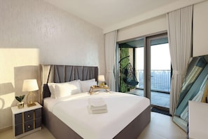 Une chambre d’hôtel comprenant un lit, des tables de chevet, une lampe, un plateau avec divers objets, une fenêtre et un balcon avec une chaise.