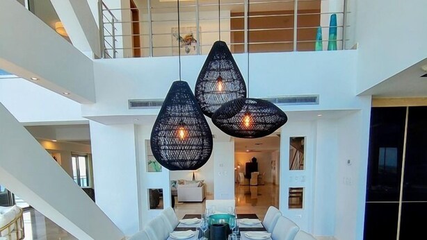 A modern dining area with a long table set for a meal, surrounded by white cushioned chairs. - ☀️🌴Dreams Come True by IRE Vacations - Luxury 5 bedrooms Condo by the Beach (Cupecoy)