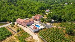 Un grand bâtiment doté d’une piscine, entouré de vignobles et d’un paysage vallonné.