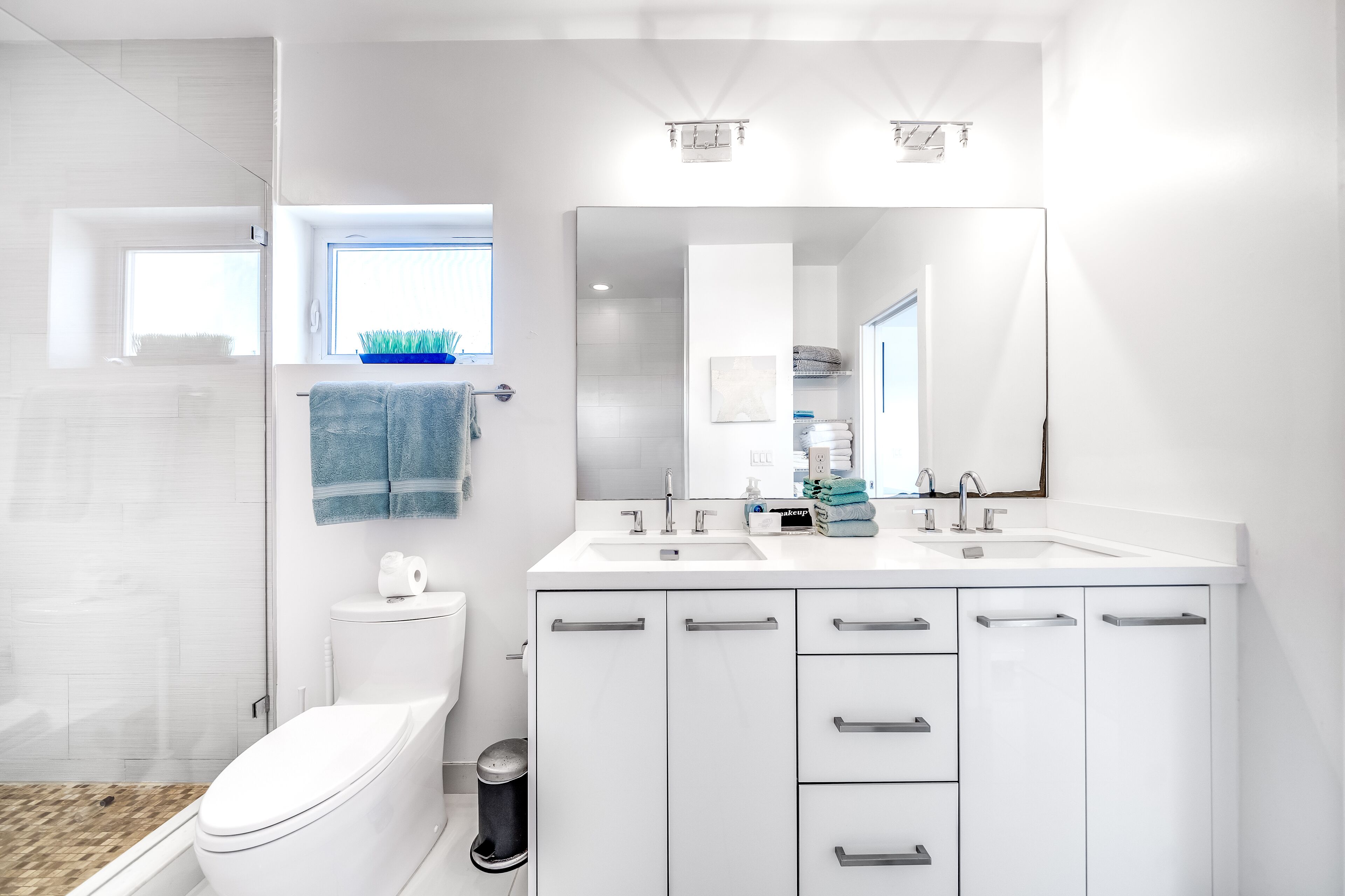 A modern bathroom with a white sink, two mirrors, and a toilet.