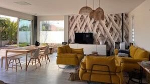 Un salon moderne doté d’un grand téléviseur, de canapés jaunes et d’un coin repas avec des meubles en bois.