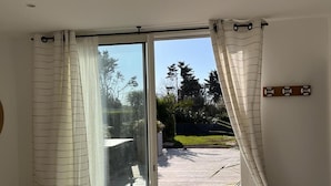 Une chambre dotée d’une grande porte-fenêtre coulissante donnant sur une terrasse extérieure.