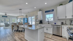 A spacious kitchen with white cabinets, a granite countertop, and a central island. - Luxurious 5 Bedroom, 5.5 Bath with Private Pool & Elevator (Garden City Beach)