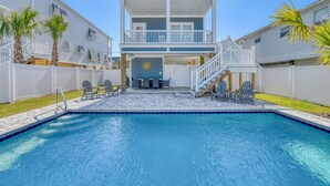 A two-story building with a pool, outdoor seating, and palm trees. - Luxurious 5 Bedroom, 5.5 Bath with Private Pool & Elevator (Garden City Beach)