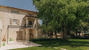 A stone building with a balcony, a door, and a large tree in the yard. - Casa Amalia with saltwater pool (Visnjan)