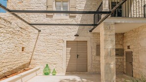 A stone building with a closed door, a balcony with a metal railing, and a staircase leading to an upper level. - Casa Amalia with saltwater pool (Visnjan)