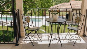 A balcony with two chairs and a table, overlooking a swimming pool and greenery. - Casa Amalia with saltwater pool (Visnjan)