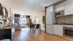 Moderni keittiö, jossa on valkoiset kaapit, sisäänrakennettu uuni ja mikroaaltouuni.