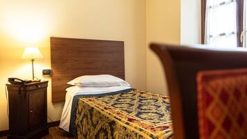 A hotel room with a bed, a nightstand with a lamp, and a wooden headboard.