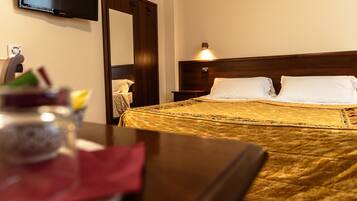 Habitación de hotel con cama, mesita de noche, lámpara, televisor en la pared y espejo.