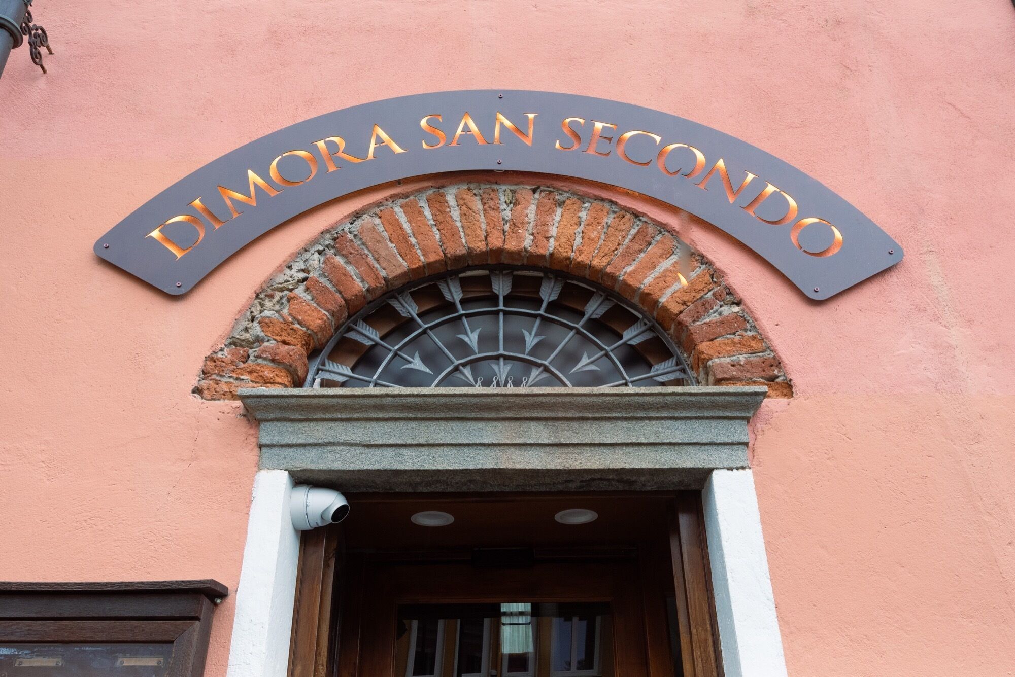 A building entrance with a sign reading "DIMORA SAN SECONDO" above a brick archway.